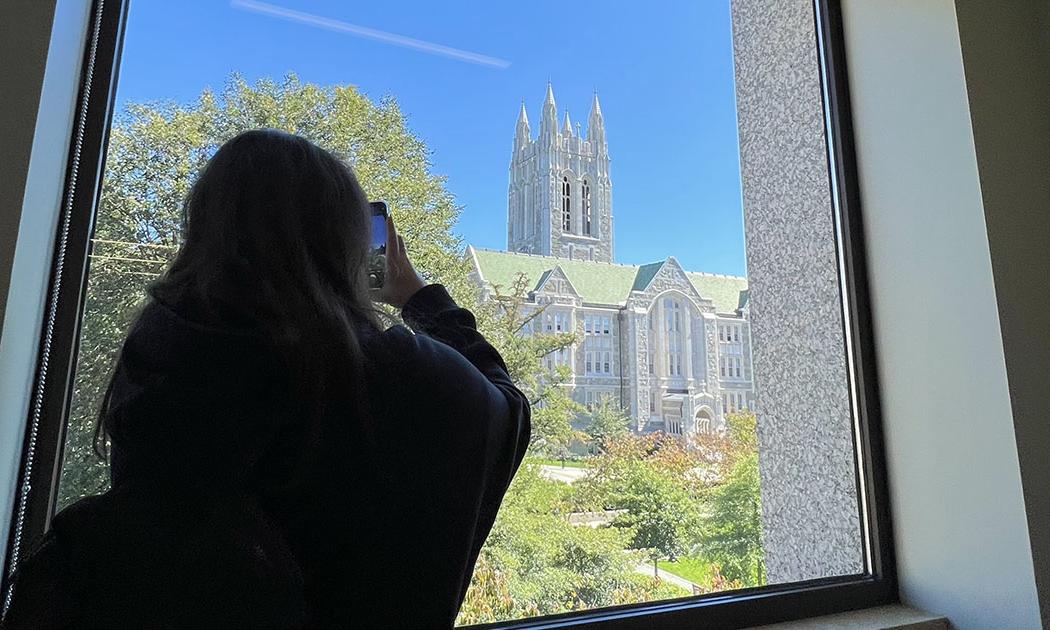 Student taking a photo of Gasson through a window