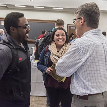 Participants 和 "recruiters" talking with each other at the STM Career Expo in Room 100 of Simboli大厅 (9 Lake St.). Photographed for the Winter '18 issue of BCM. Dan Leahy of BC校园事工 talks with Dalia Gutierrez, 硕士二年级学生 和 John Gabelus, 硕士二年级学生.