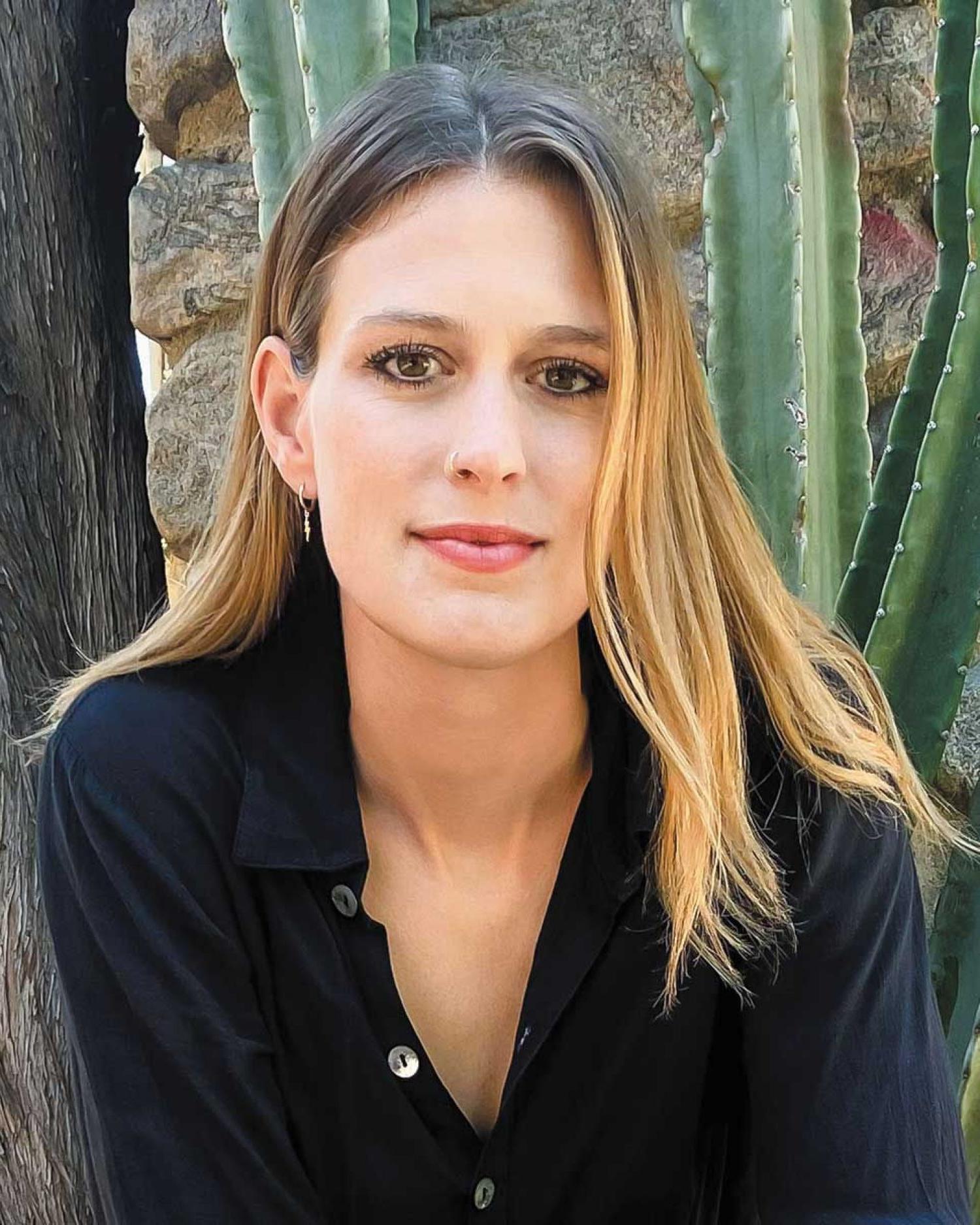 Elizabeth Flock photographed in front of cactus and stonewall.