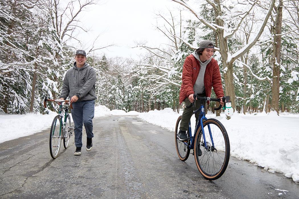 两个年轻人在下雪的路上骑自行车