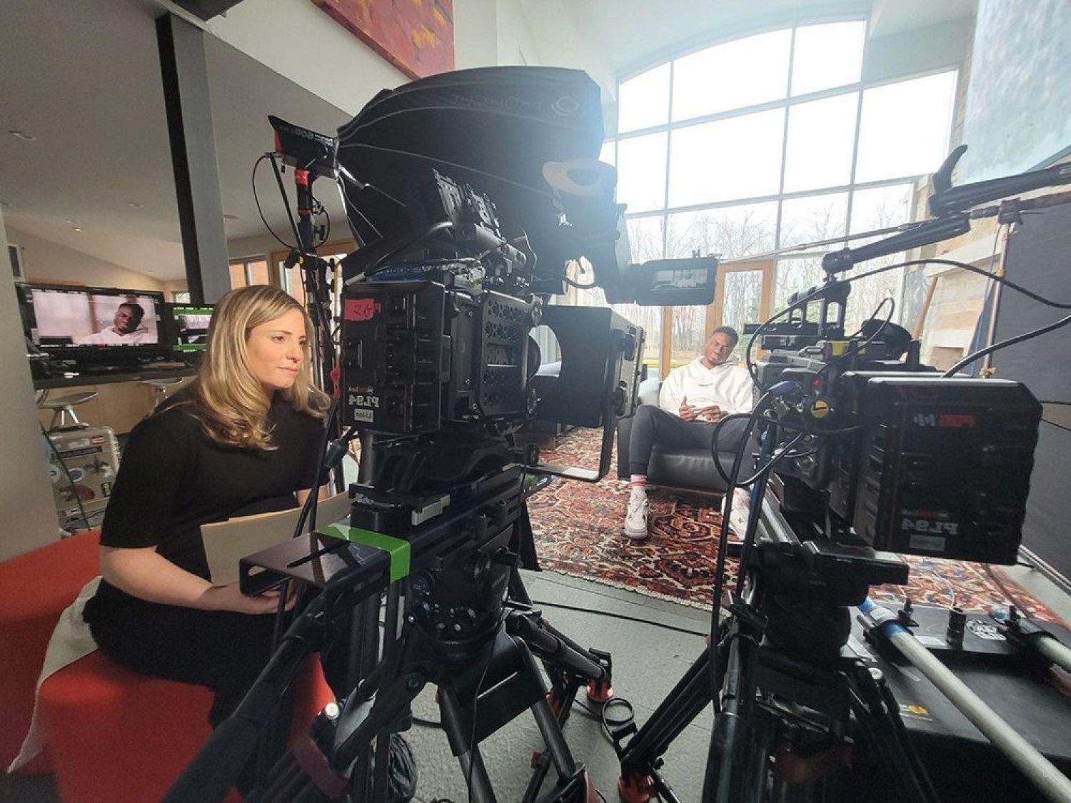 Kristen Lappas in the director's chair with Giannis sitting in the background