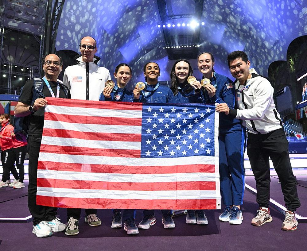 A group of people standing behind an American flag